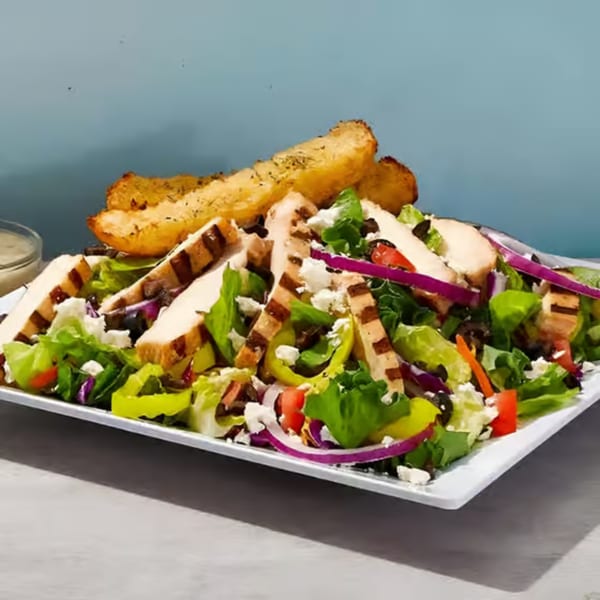 Grilled chicken salad with lettuce, tomatoes, onions, peppers, feta, olives, and garlic bread.